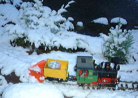 LGB®-Lok Stainz mit zum Schneepflug umgebauten Feldbahn-Kastenwagen bei ersten Schneeräumversuchen im frischen Neuschnee